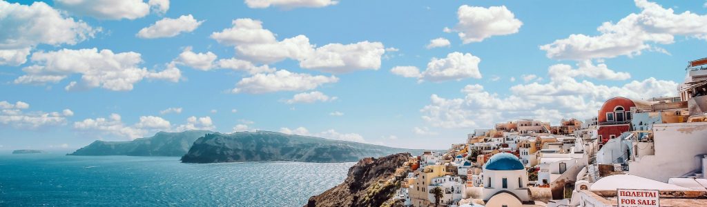 White Concrete House Near Body of Water Under White and Blue Cloudy Sky