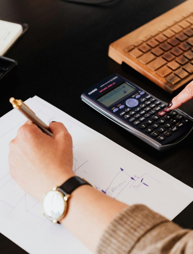 Bookkeeper Writing Down on Paper while using Calculator