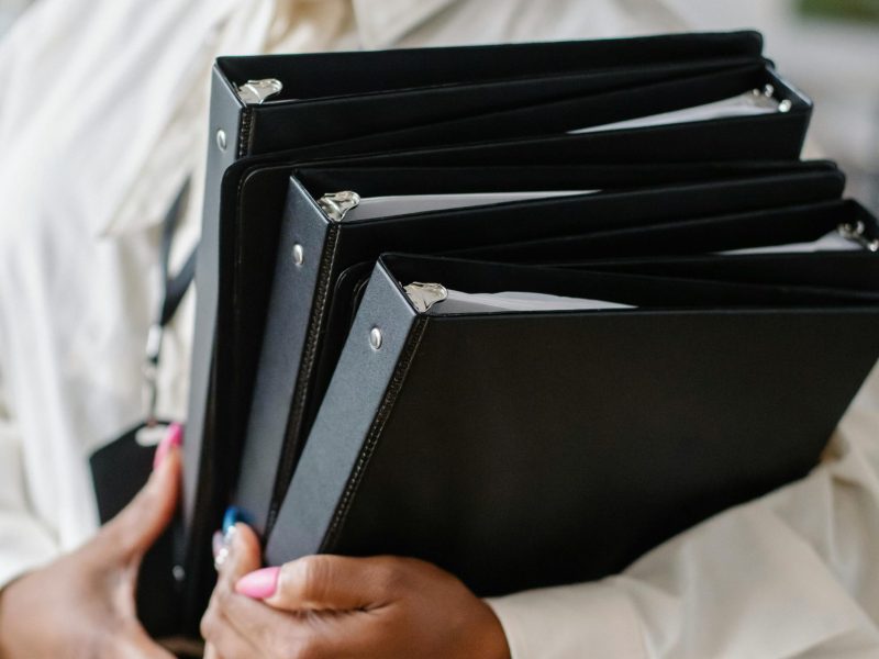 Black woman carrying pile of documents in office